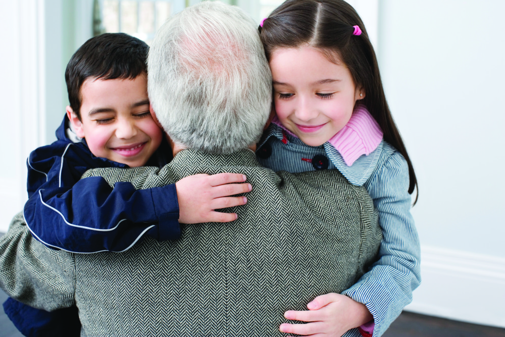 Brother and sister hugging grandfather